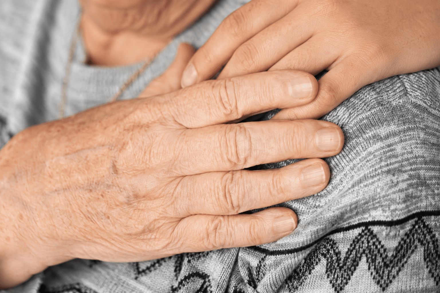 Eine junge Hand hält behutsam die Hand eines älteren Menschen
